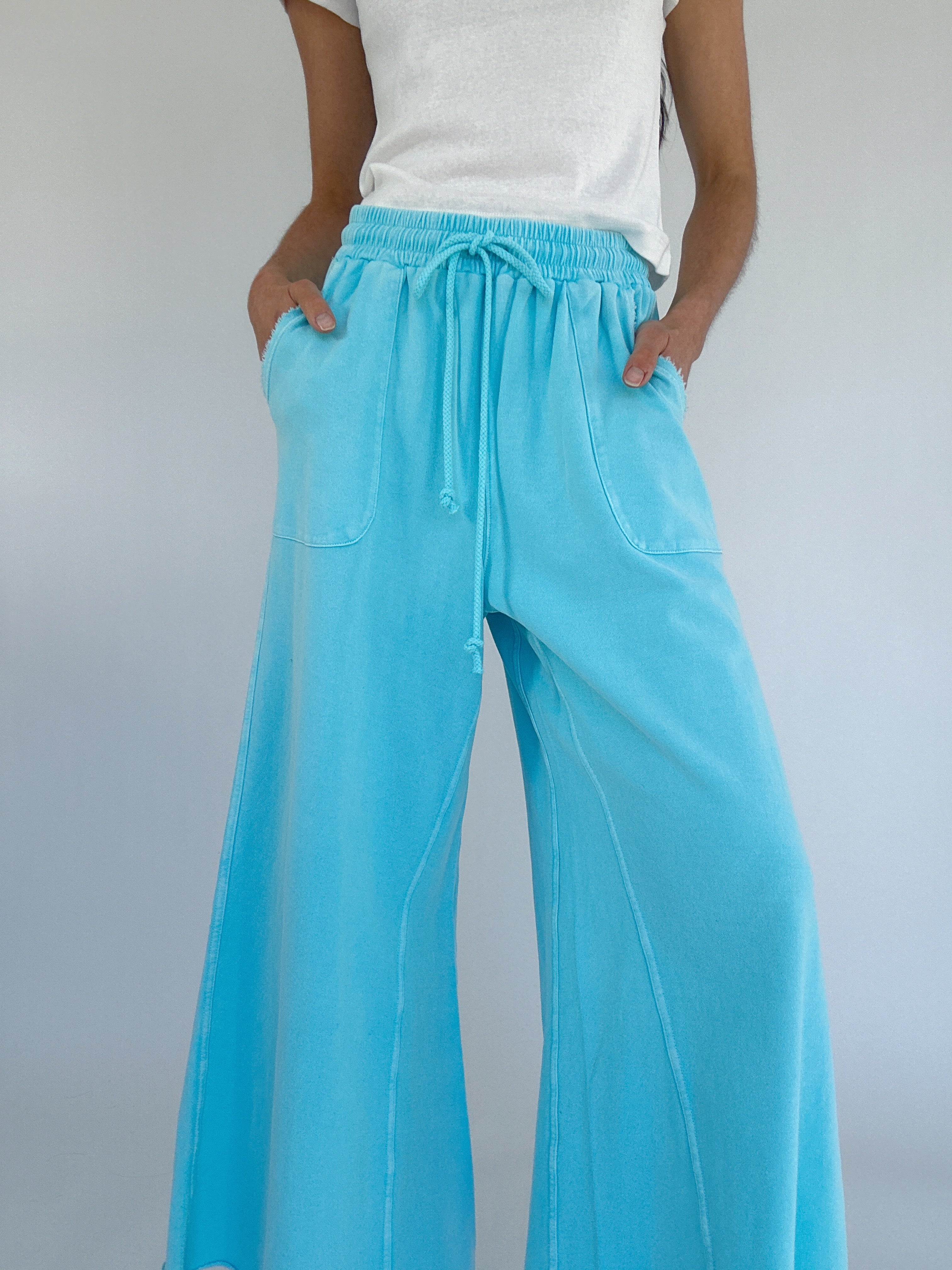 Light blue wide-leg pants with a drawstring waist and pockets worn by a person on a plain background 
