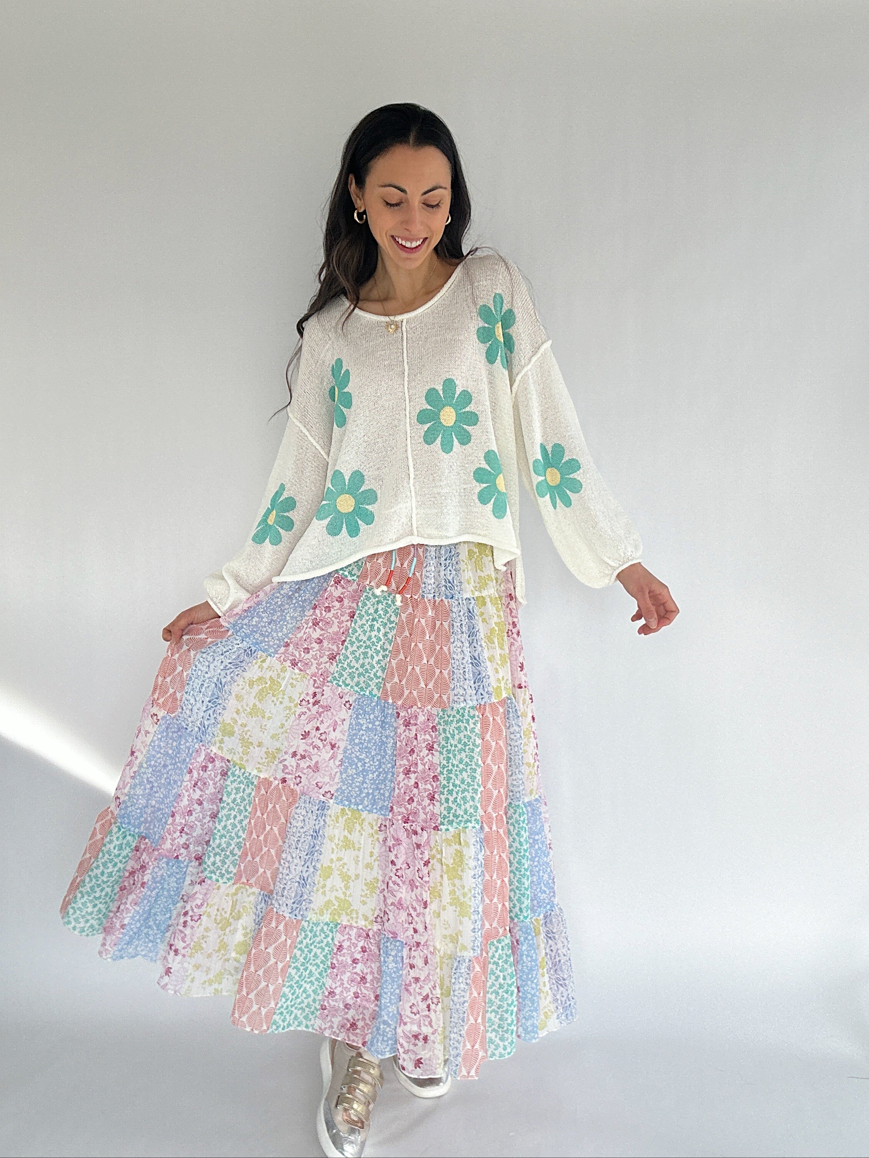 Woman wearing a floral top and patchwork skirt against a white background