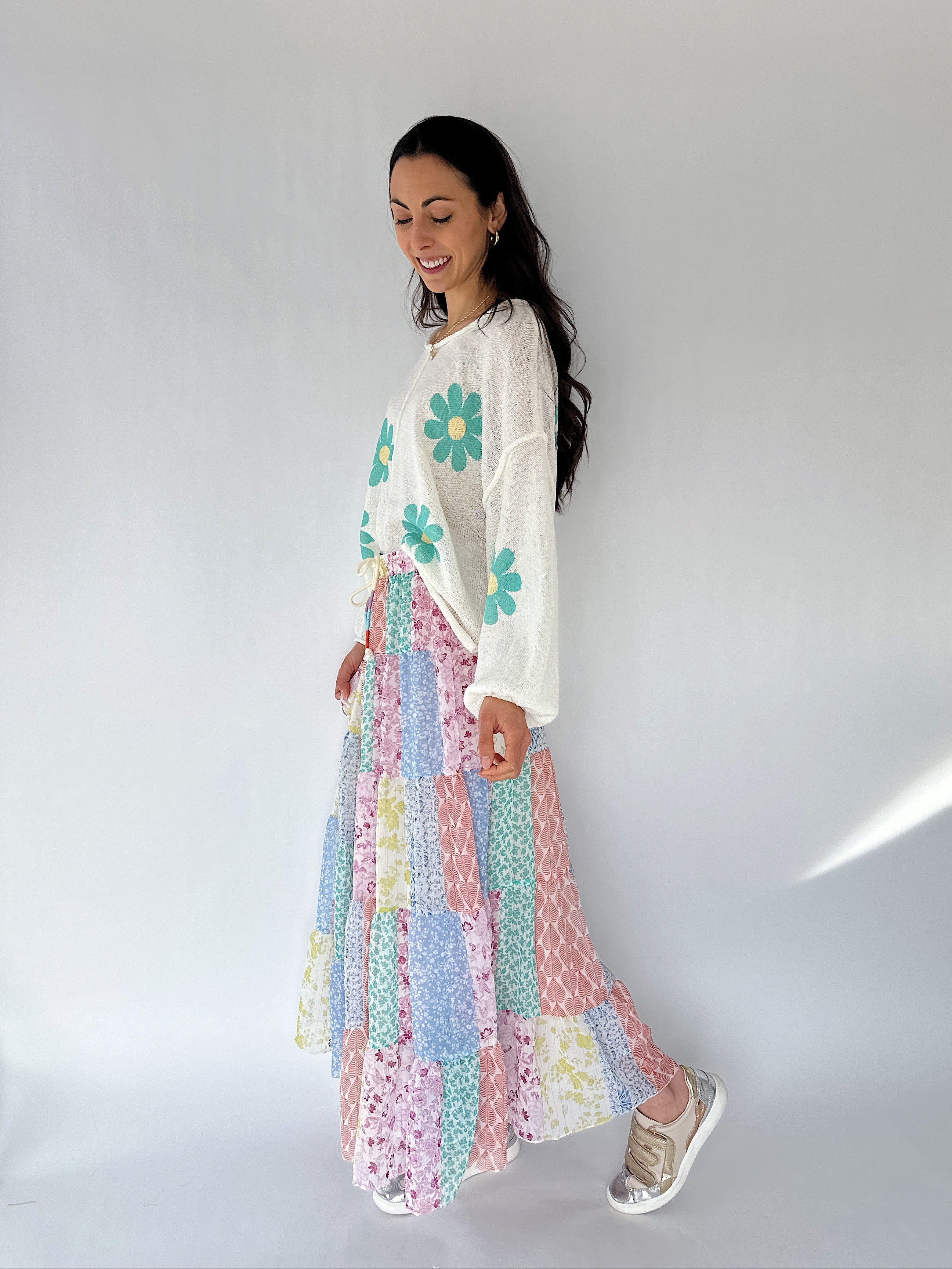 Woman wearing a floral knit top and maxi skirt against a plain background