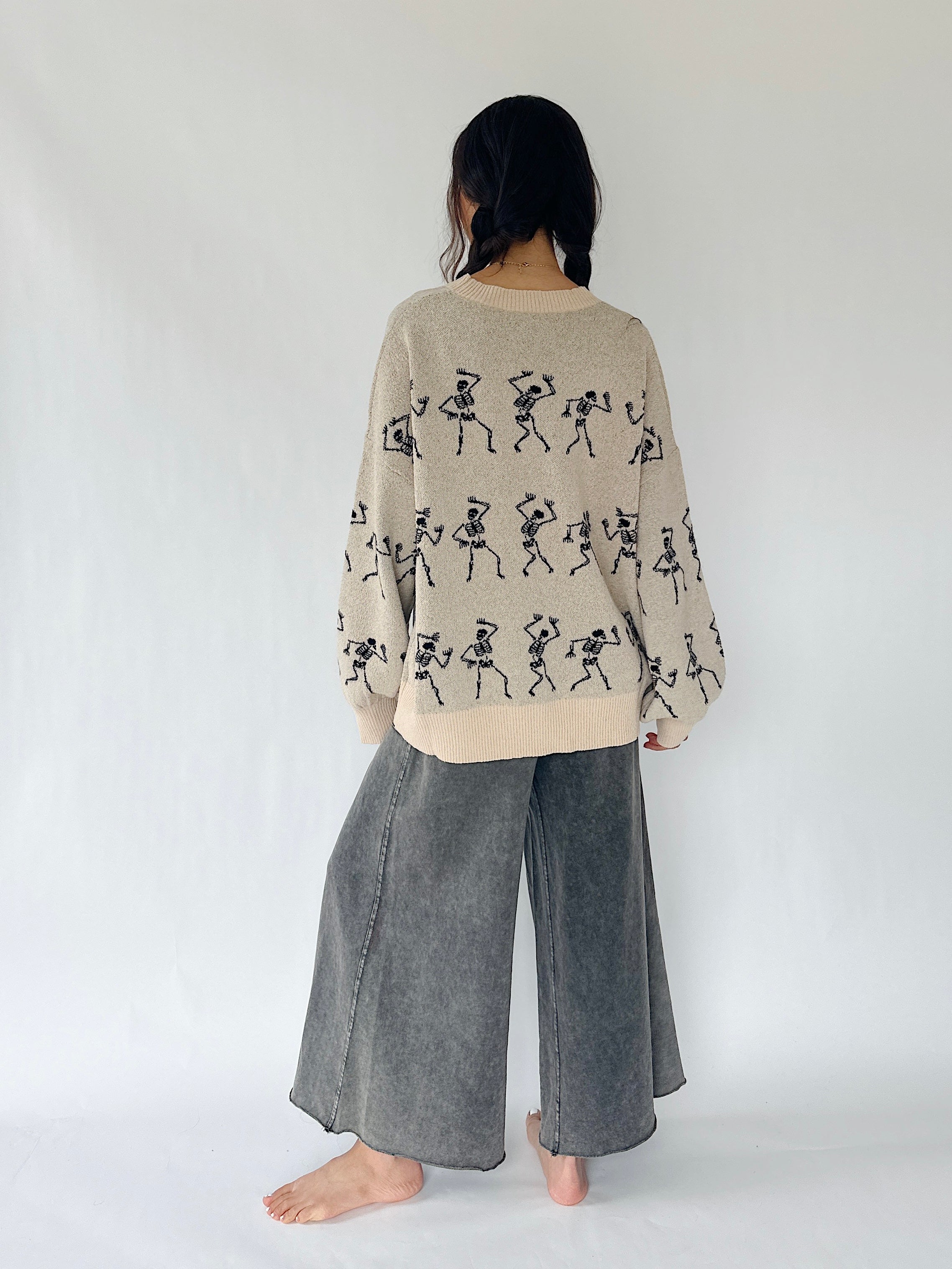 woman standing from the back with dancing skeletons all over