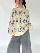 woman wearing cream sweater with dancing skeletons all over