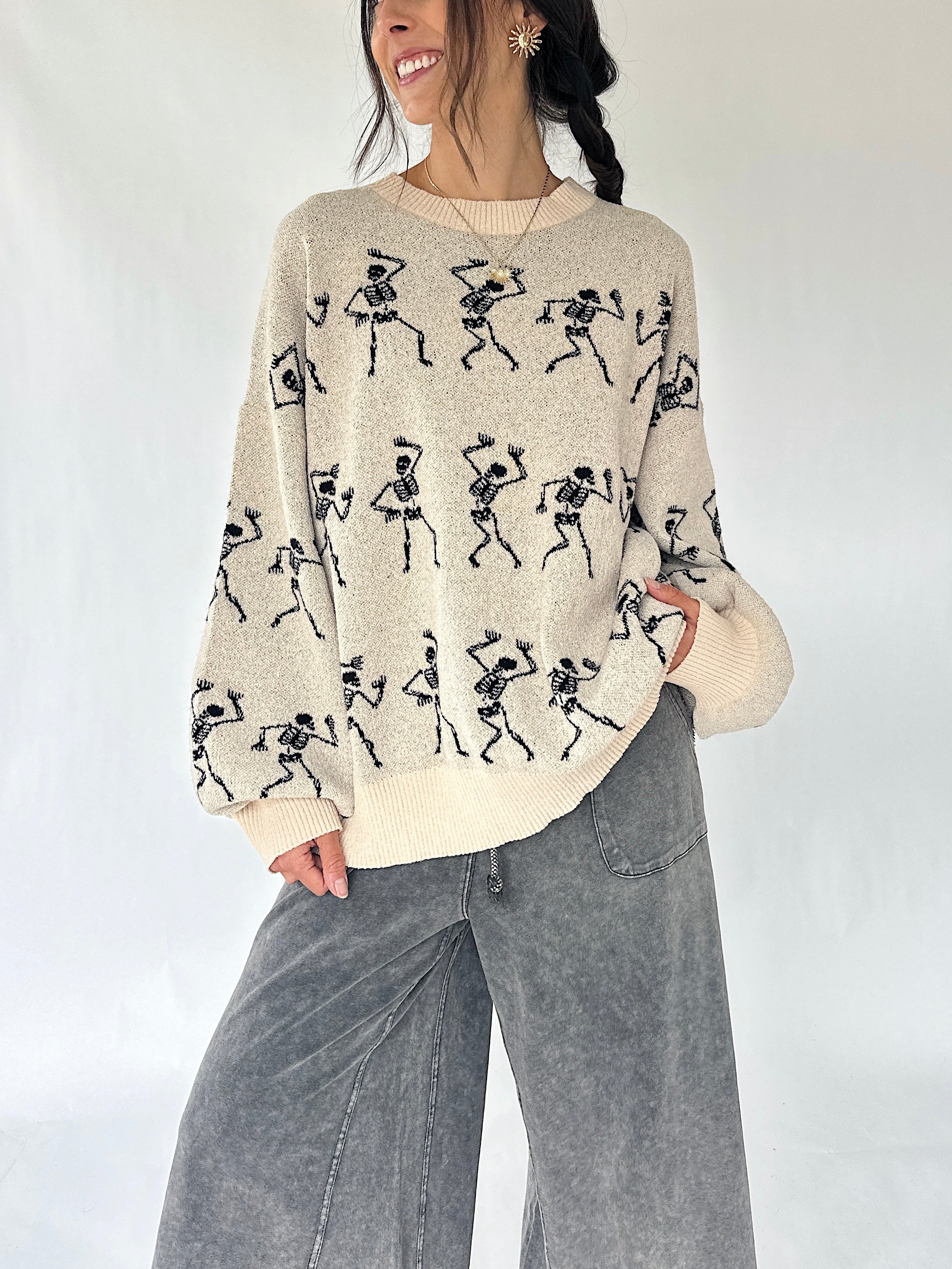 woman wearing cream sweater with dancing skeletons all over