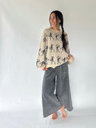 woman wearing dancing skeleton sweater with grey wide leg sweatpants