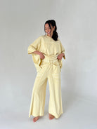 Woman wearing a light yellow outfit on a plain background