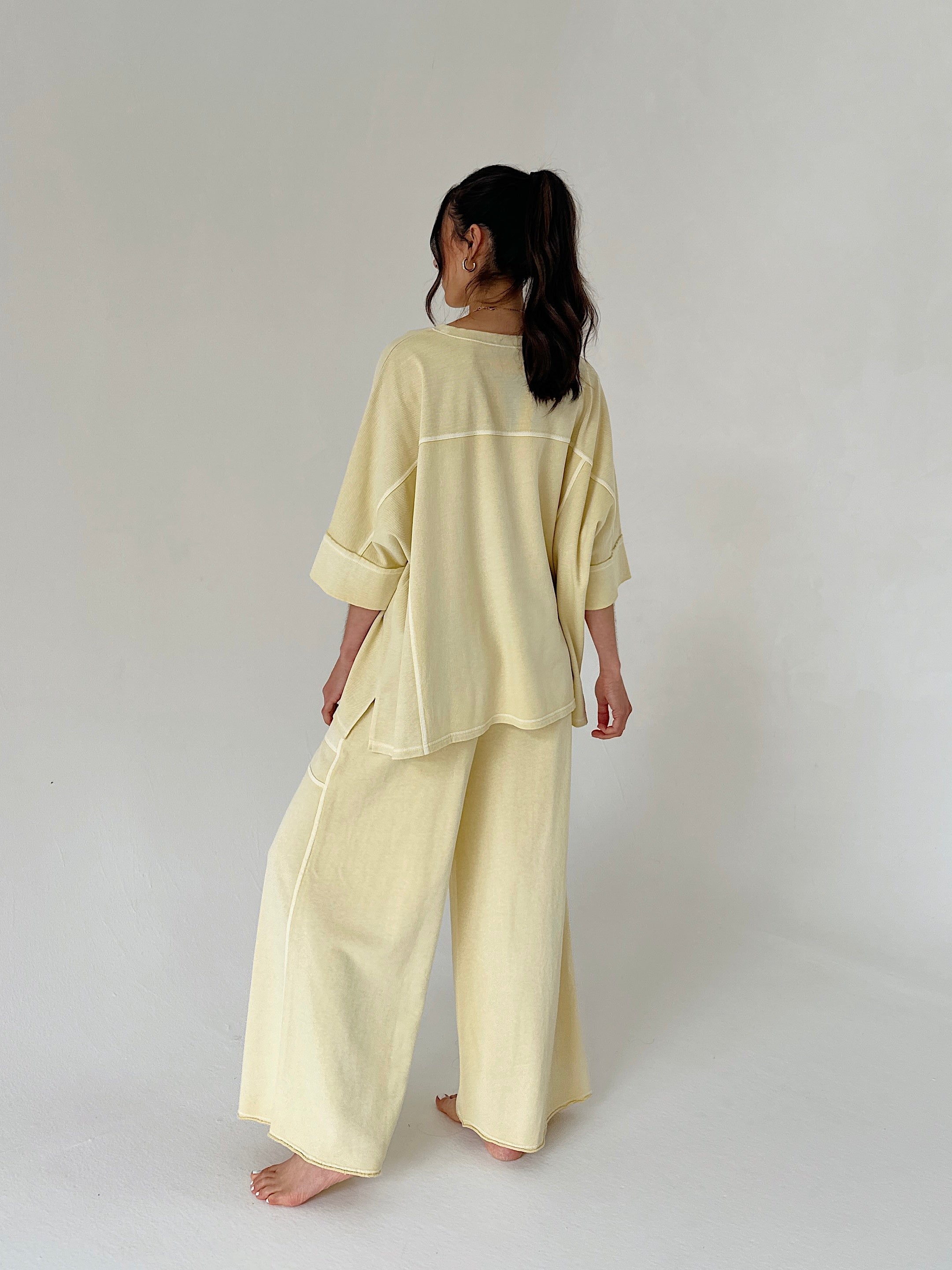 Person wearing a light yellow outfit on a plain background from back