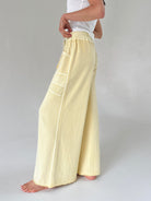 Person wearing light yellow wide-leg pants on a plain background