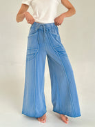 Person wearing blue wide-leg pants with seaming on a plain background