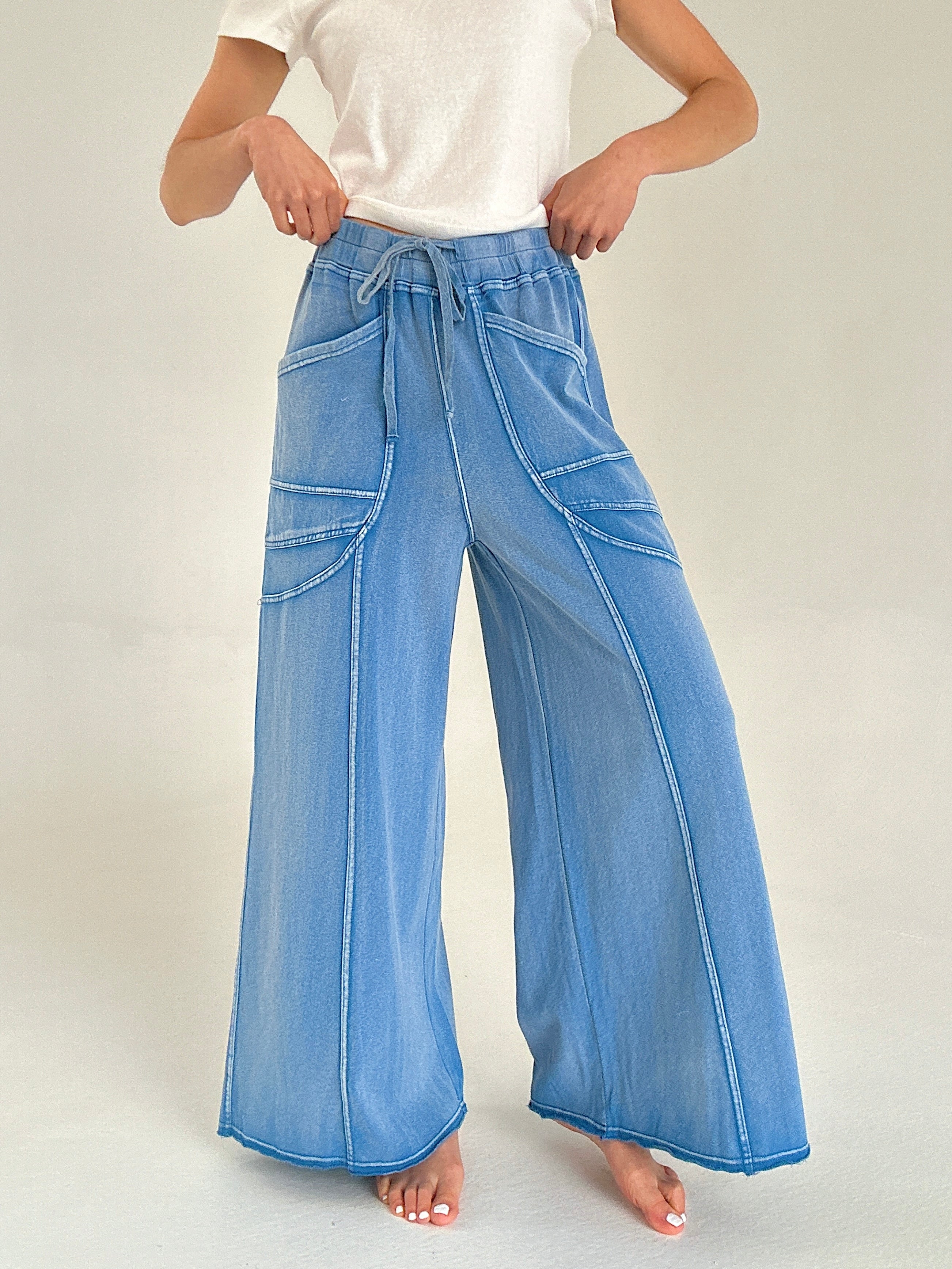 Person wearing blue wide-leg pants with seaming on a plain background