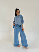 Woman wearing a blue outfit with wide-leg pants on a white background