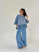 Woman wearing a blue lounge outfit with an oversized top and wide-leg pants on a white background