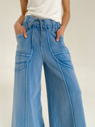 Person wearing blue wide-leg pants with a drawstring waist and pockets on a white background