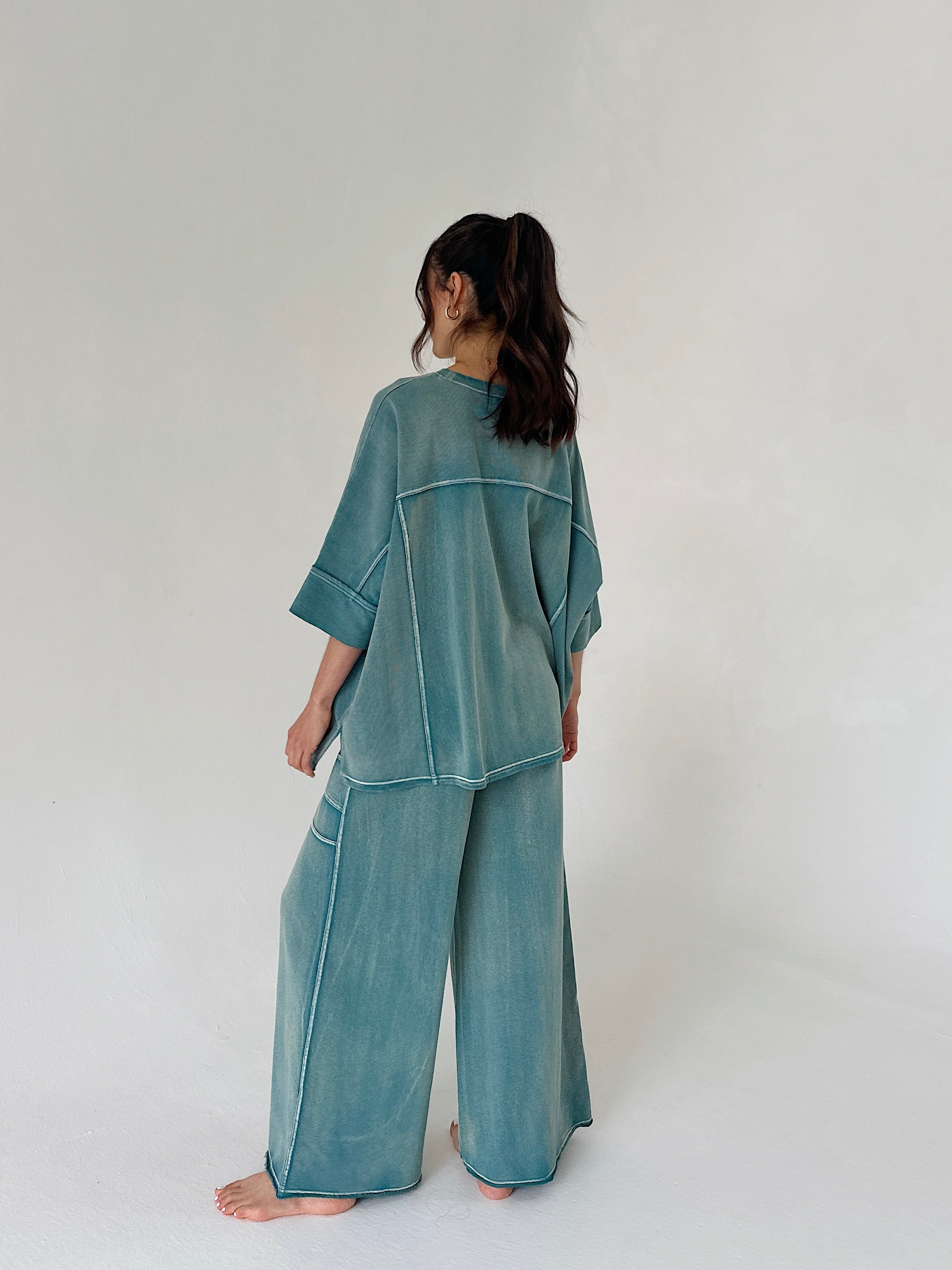 Person wearing a teal outfit on a white background from back