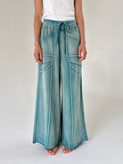 Wide-leg pants in washed teal worn by a person on a plain background