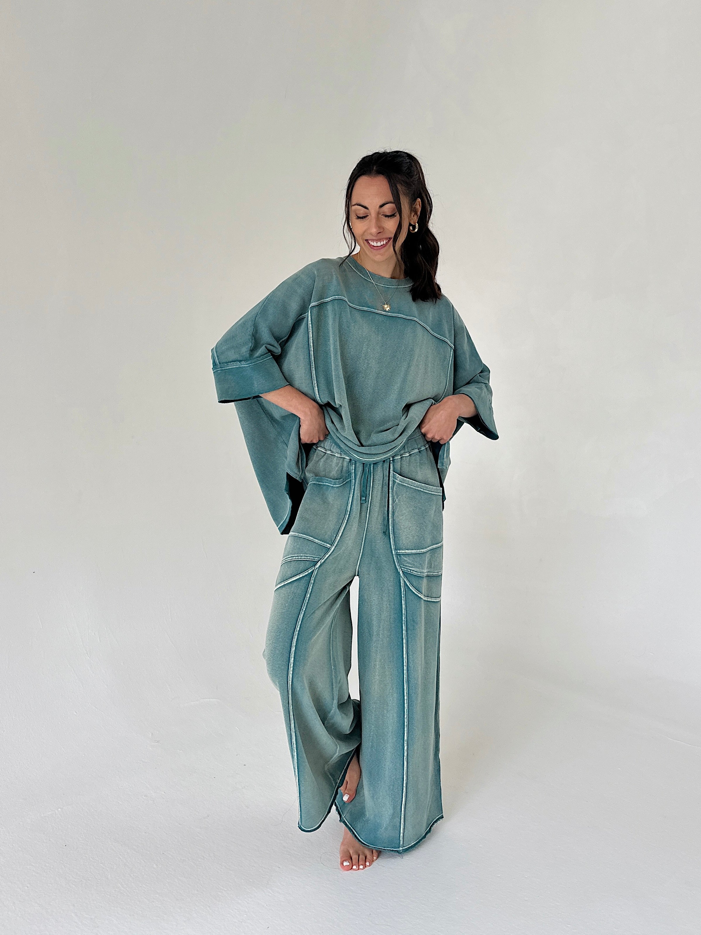 Woman wearing a teal outfit with wide-leg pants on a white background