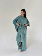 Woman wearing a teal outfit with wide-leg pants on a white background