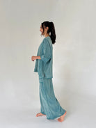 Woman wearing a teal loungewear set on a plain background