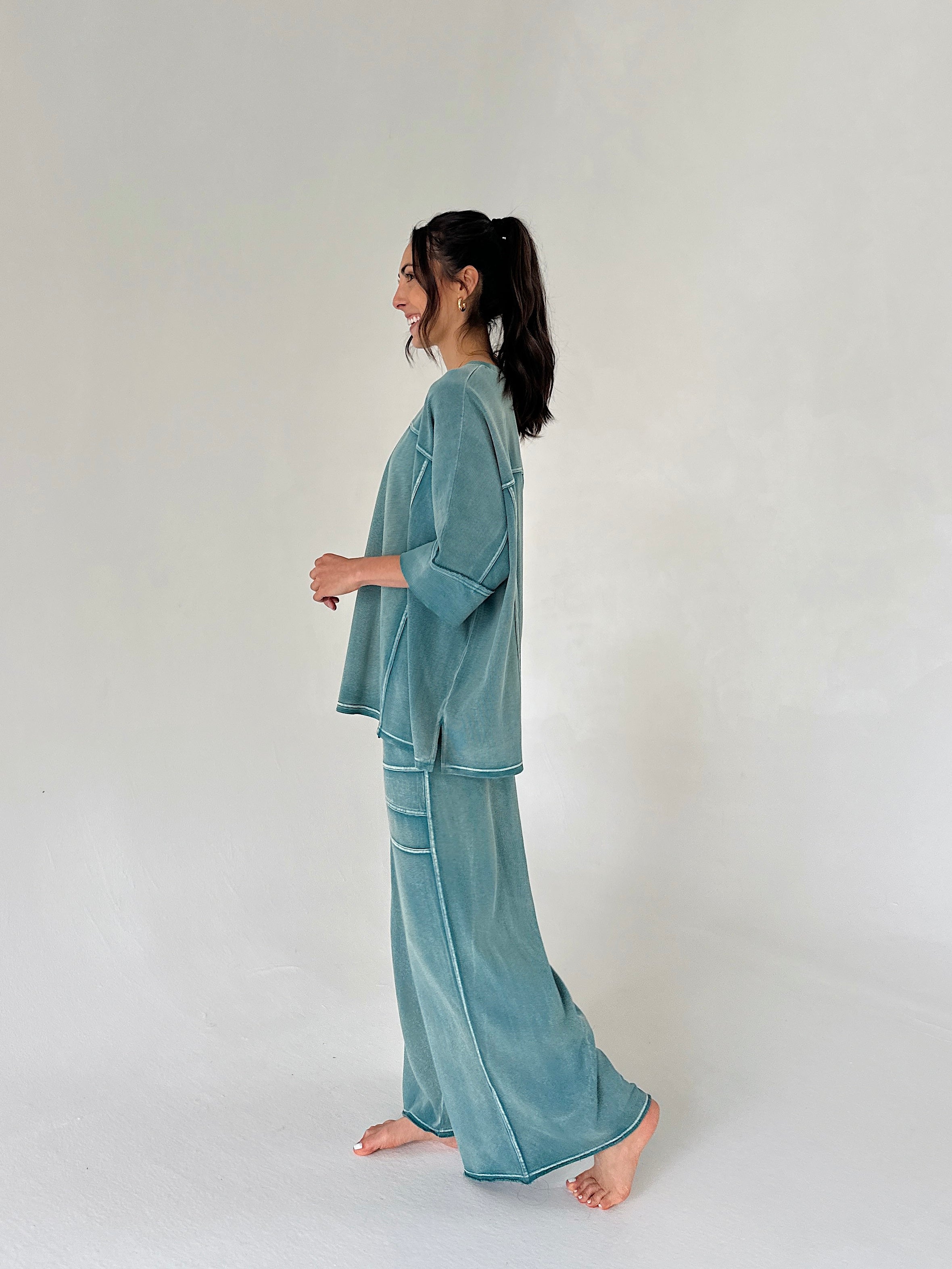 Woman wearing a teal loungewear set on a plain background