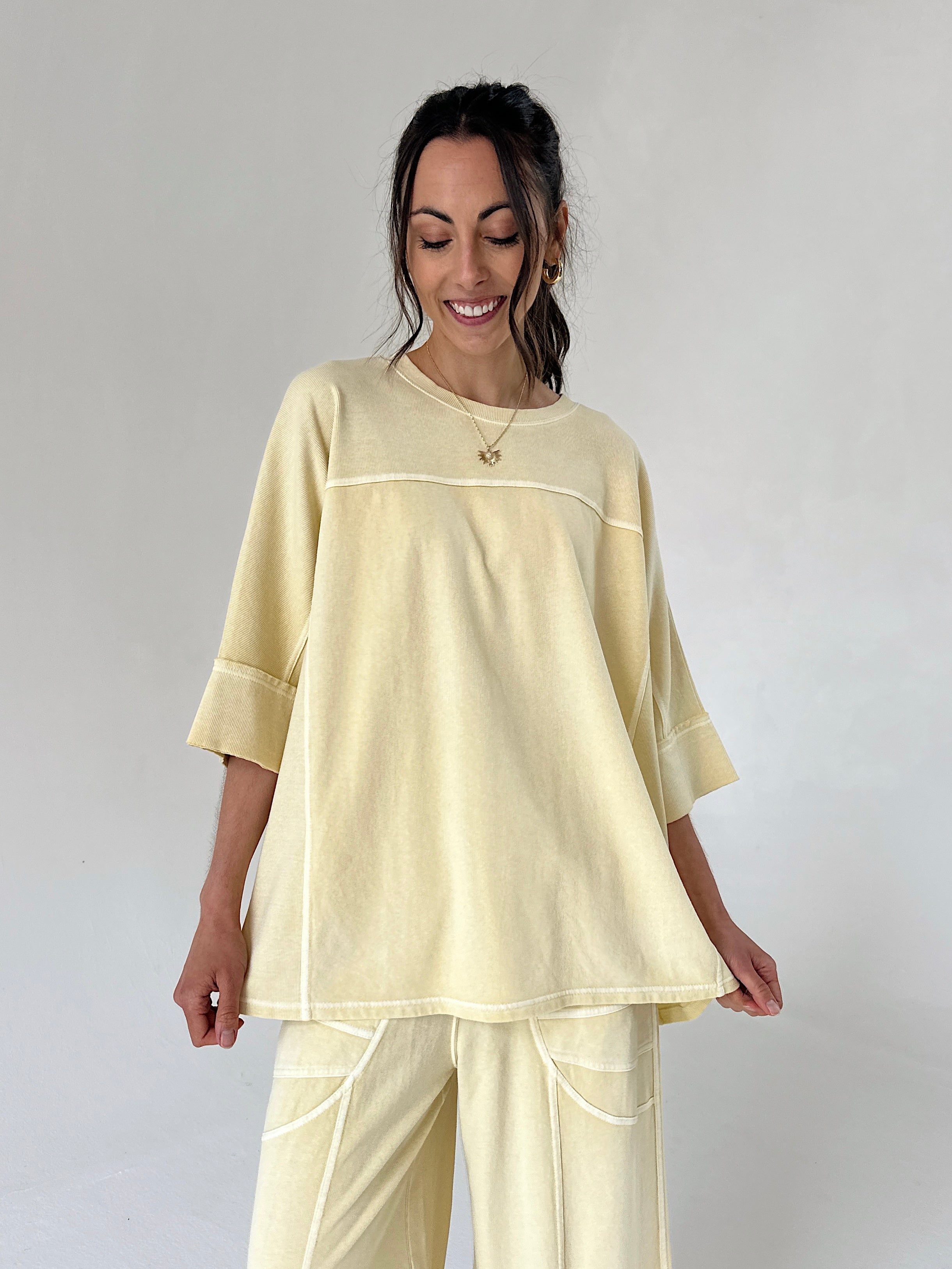 Woman wearing a light yellow outfit against a plain background
