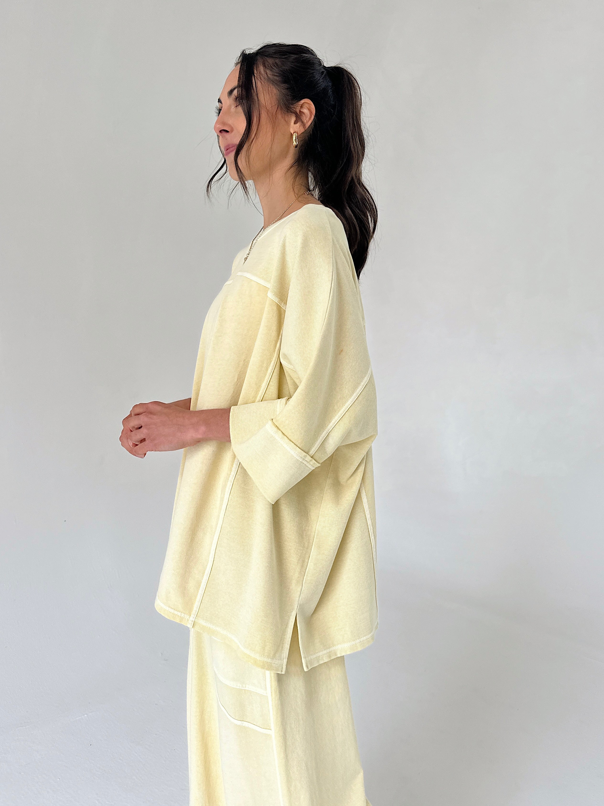 Woman wearing a light yellow outfit against a plain background