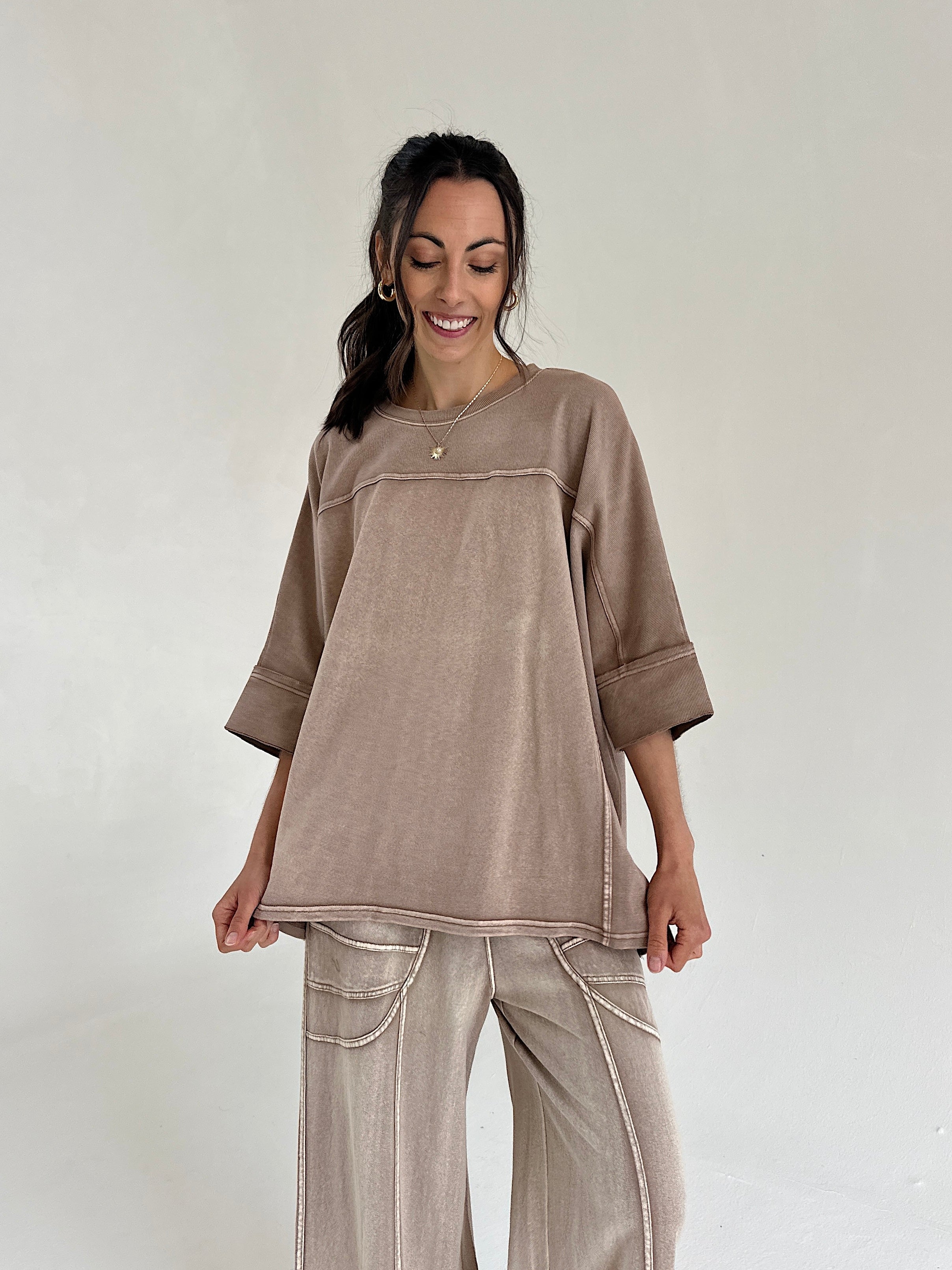 Woman wearing a brown top and pants set on a plain background