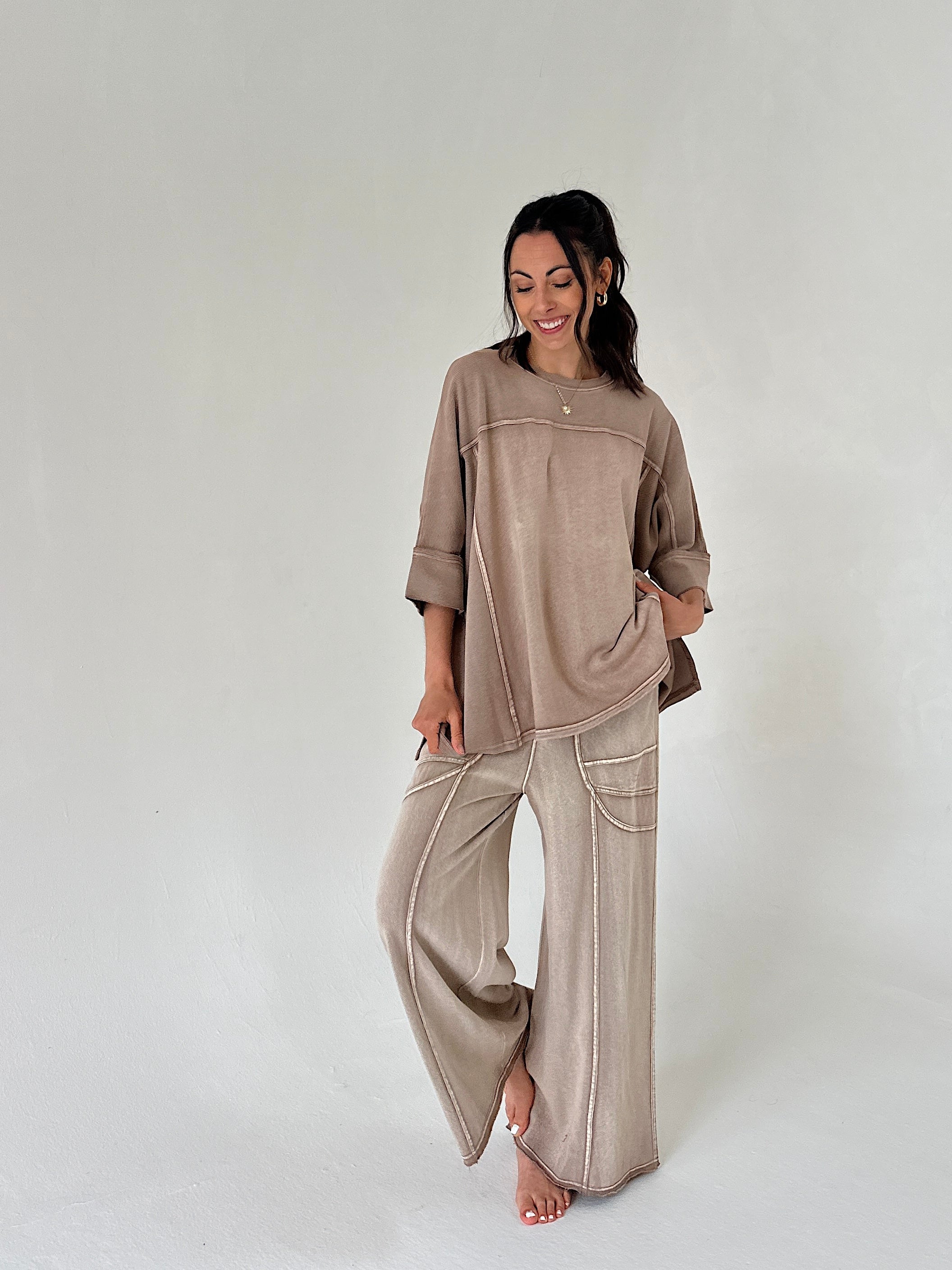 Woman wearing a beige outfit with wide-leg pants on a white background