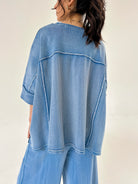 Person wearing a blue lounge outfit with a plain background showing top back
