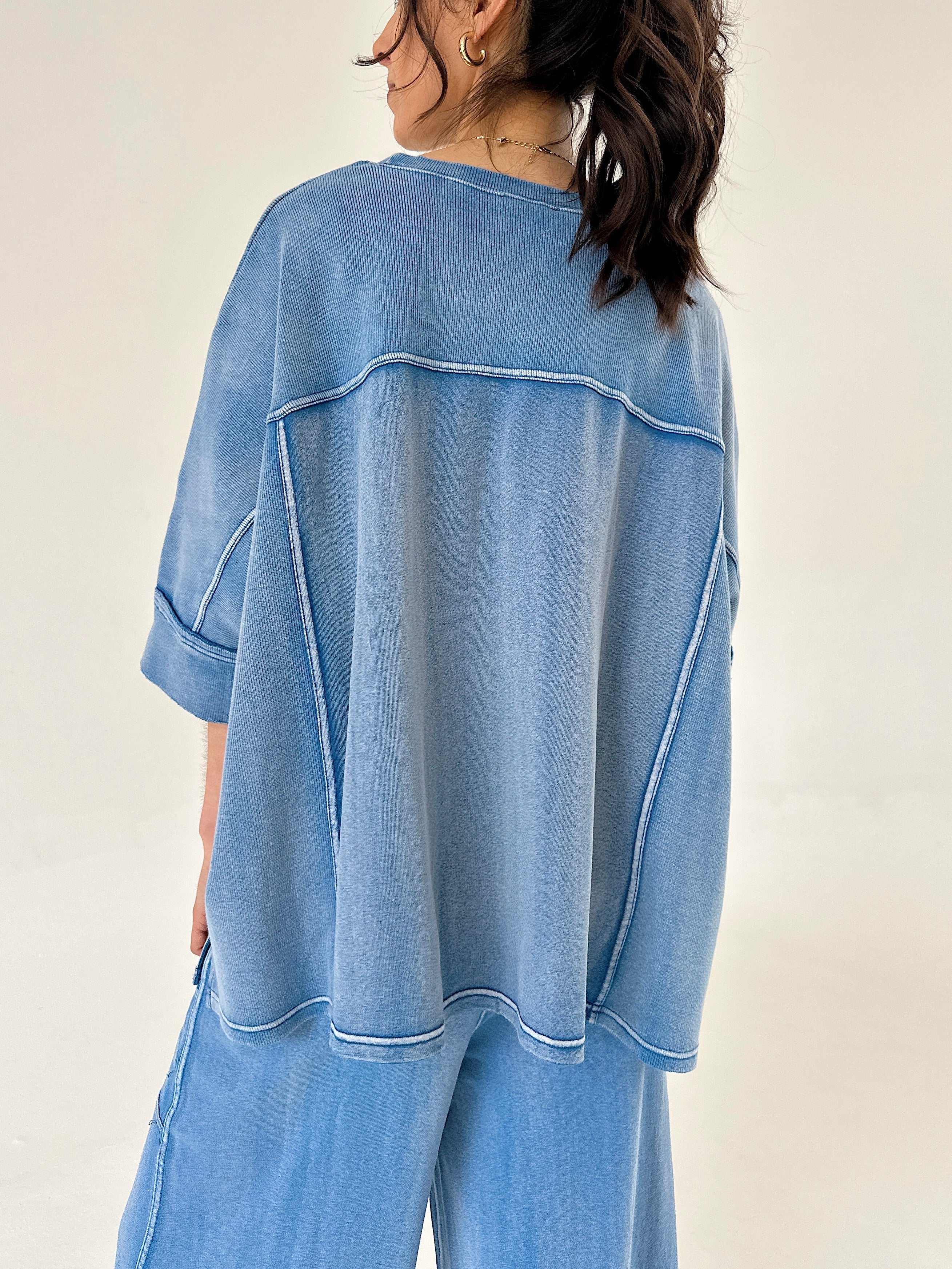 Person wearing a blue lounge outfit with a plain background showing top back