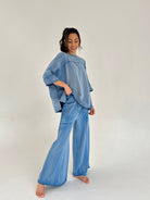 Woman wearing a blue outfit with a matching top and wide-leg pants on a white background
