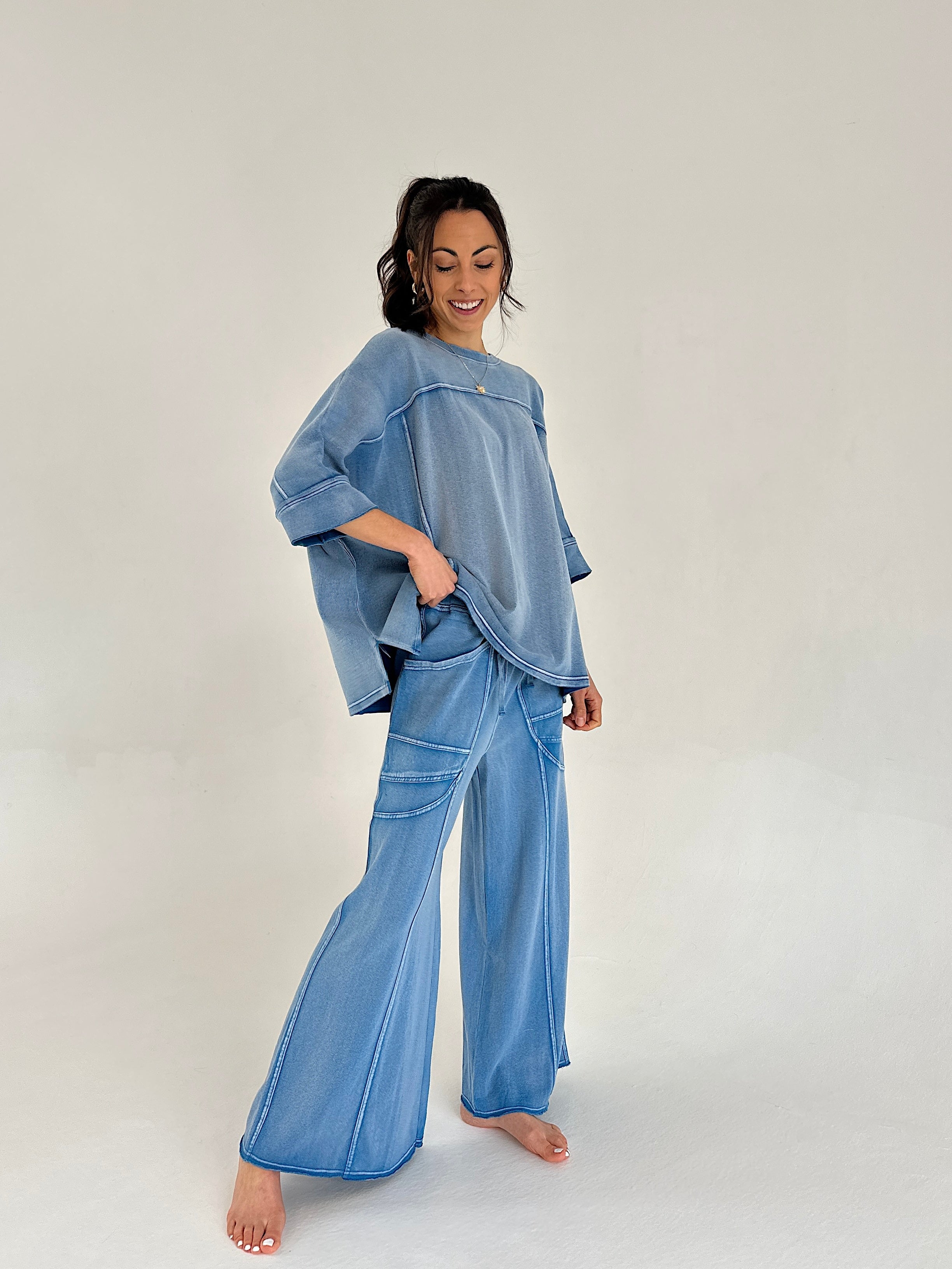 Woman wearing a blue outfit with a matching top and wide-leg pants on a white background