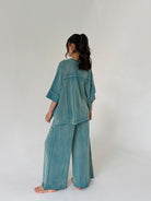 Person wearing a teal outfit on a white background from back