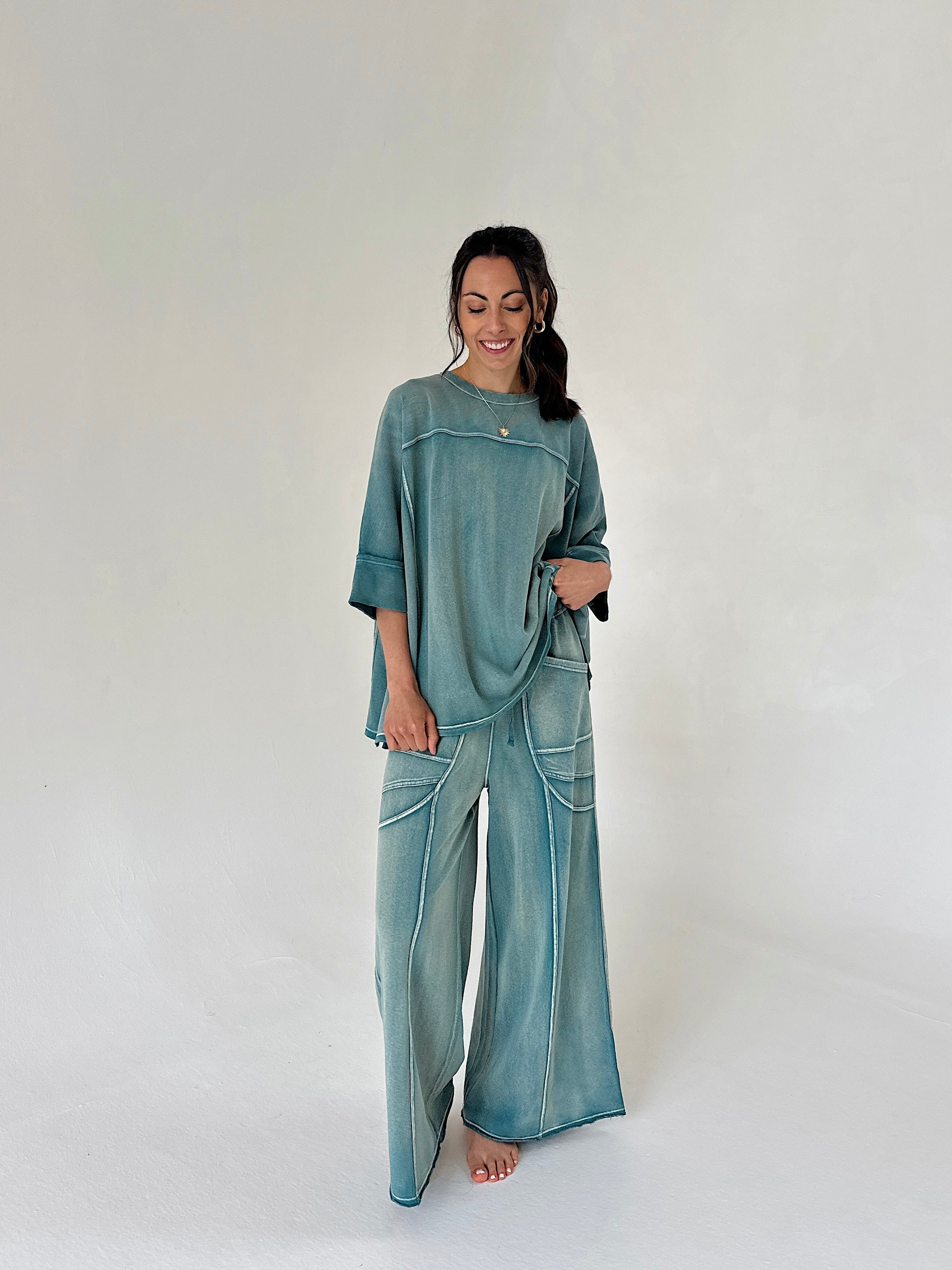 Woman wearing a teal outfit with wide-leg pants on a white background
