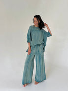 Woman wearing a teal outfit on a white background