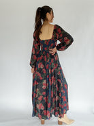 Woman wearing a floral dress with long sleeves on a white background showing back