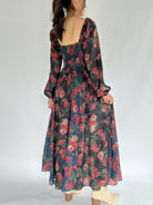 Woman wearing a floral dress with a plain background showing back view