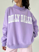 Person wearing a purple sweatshirt with 'Dilly Dally' text on a plain background