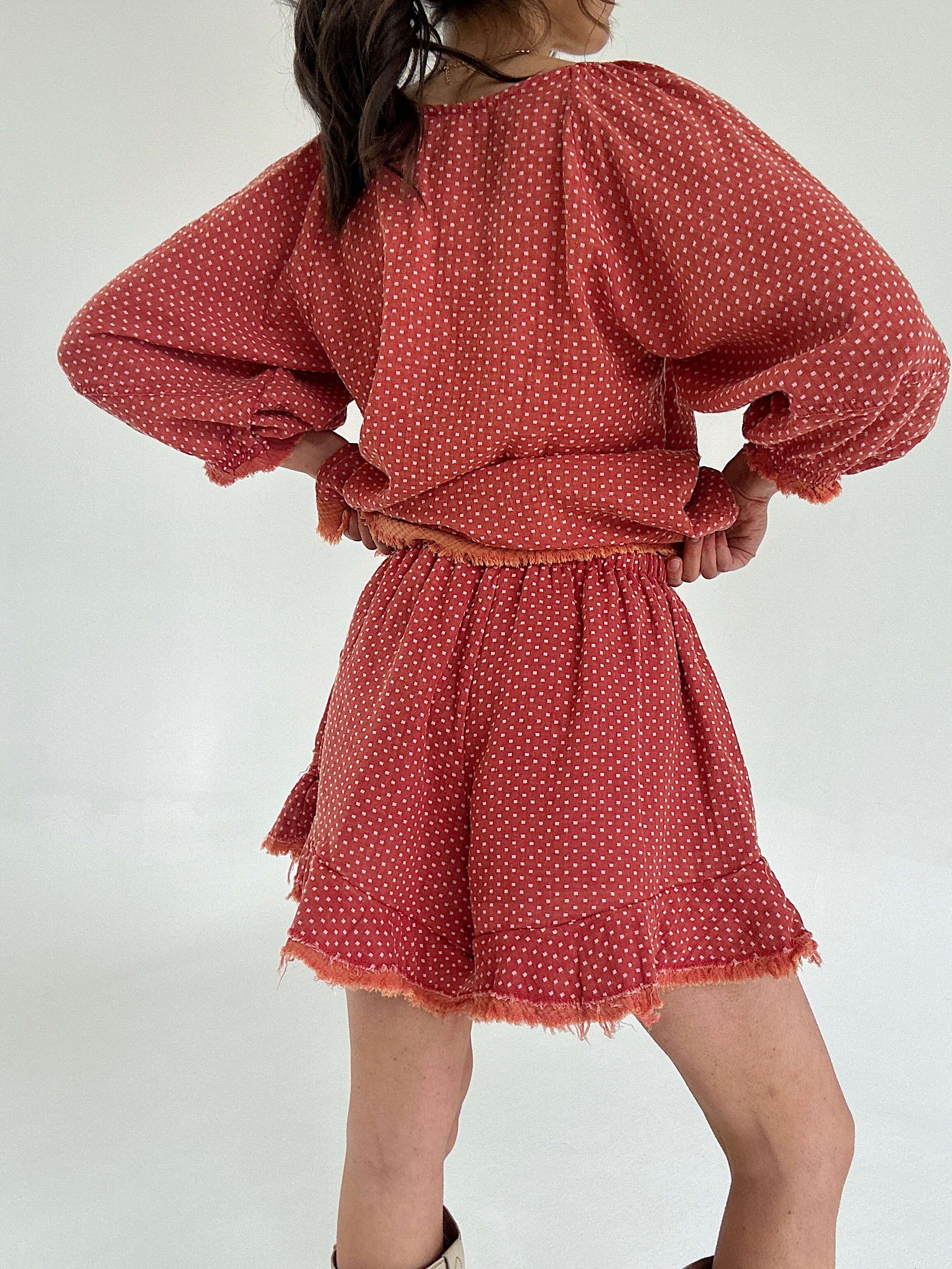 Person wearing a red polka dot set with ruffle shorts from back on a white background