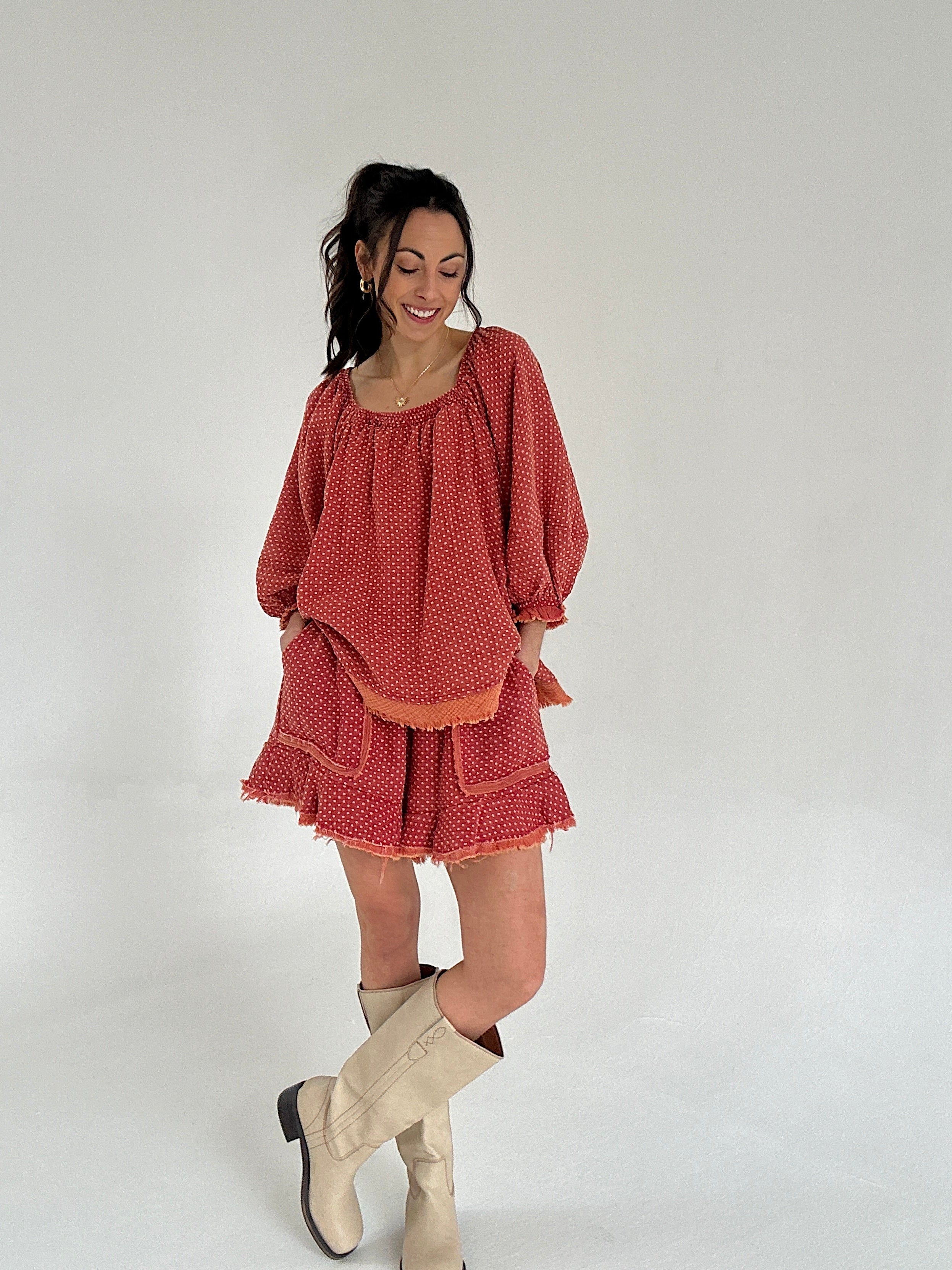 Woman wearing a red polka dot set and beige boots on a white background