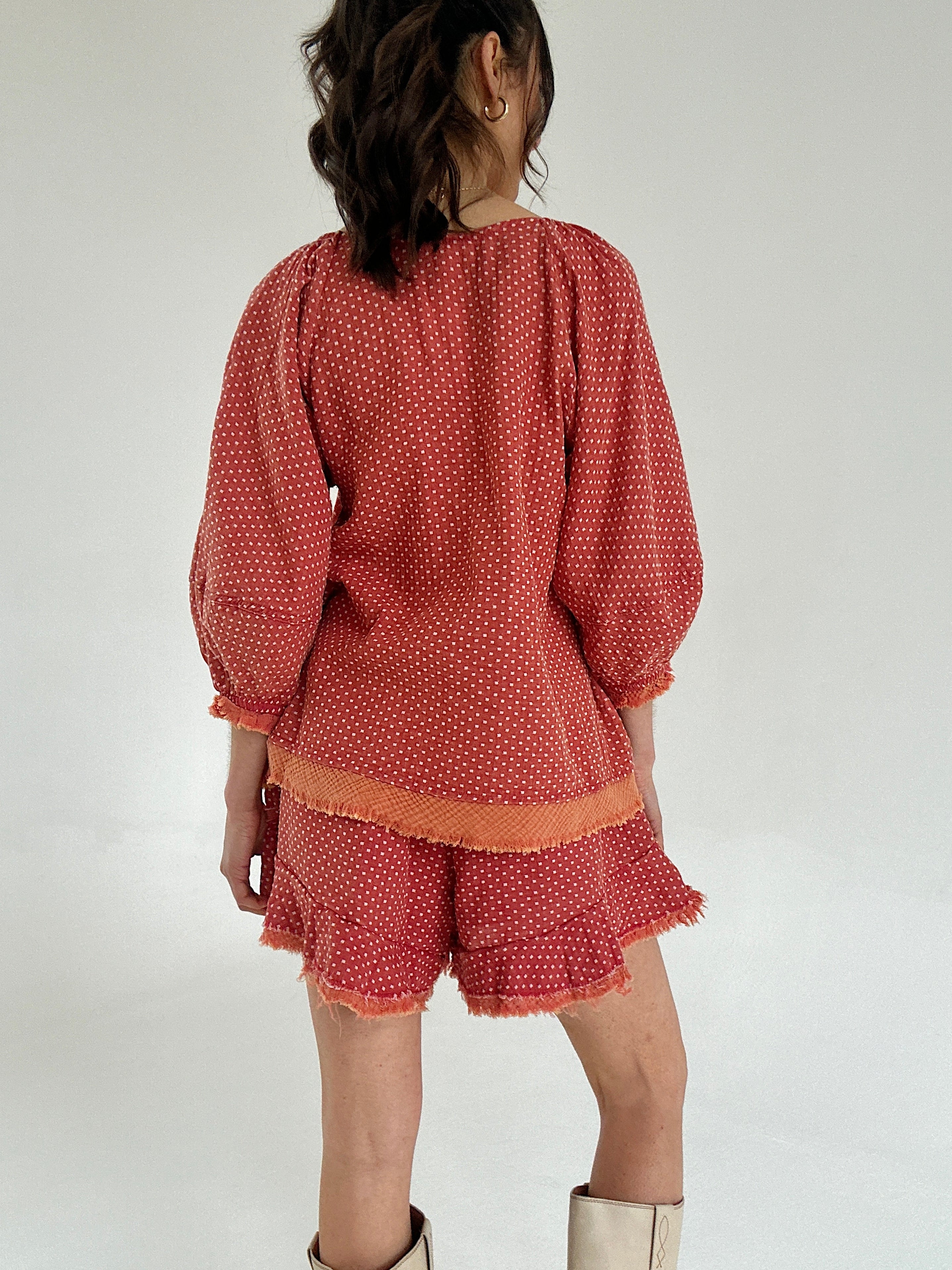 Person wearing a rust-colored polka dot outfit on a white background