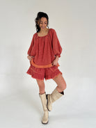 Woman wearing a red matching set and beige boots on a white background