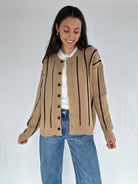 Woman wearing a beige cardigan with black stripes on a white background