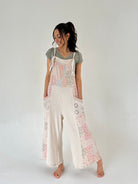 Woman wearing a terry knit jumper with patchwork print and side pockets on a plain background