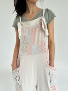 Person wearing a floral patchwork print overall jumper over a green shirt on a white background