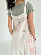 Person wearing a light-colored floral jumper over a green shirt on a plain background showing back button detail