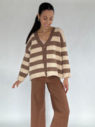 Woman wearing a brown and beige striped cardigan against a white background