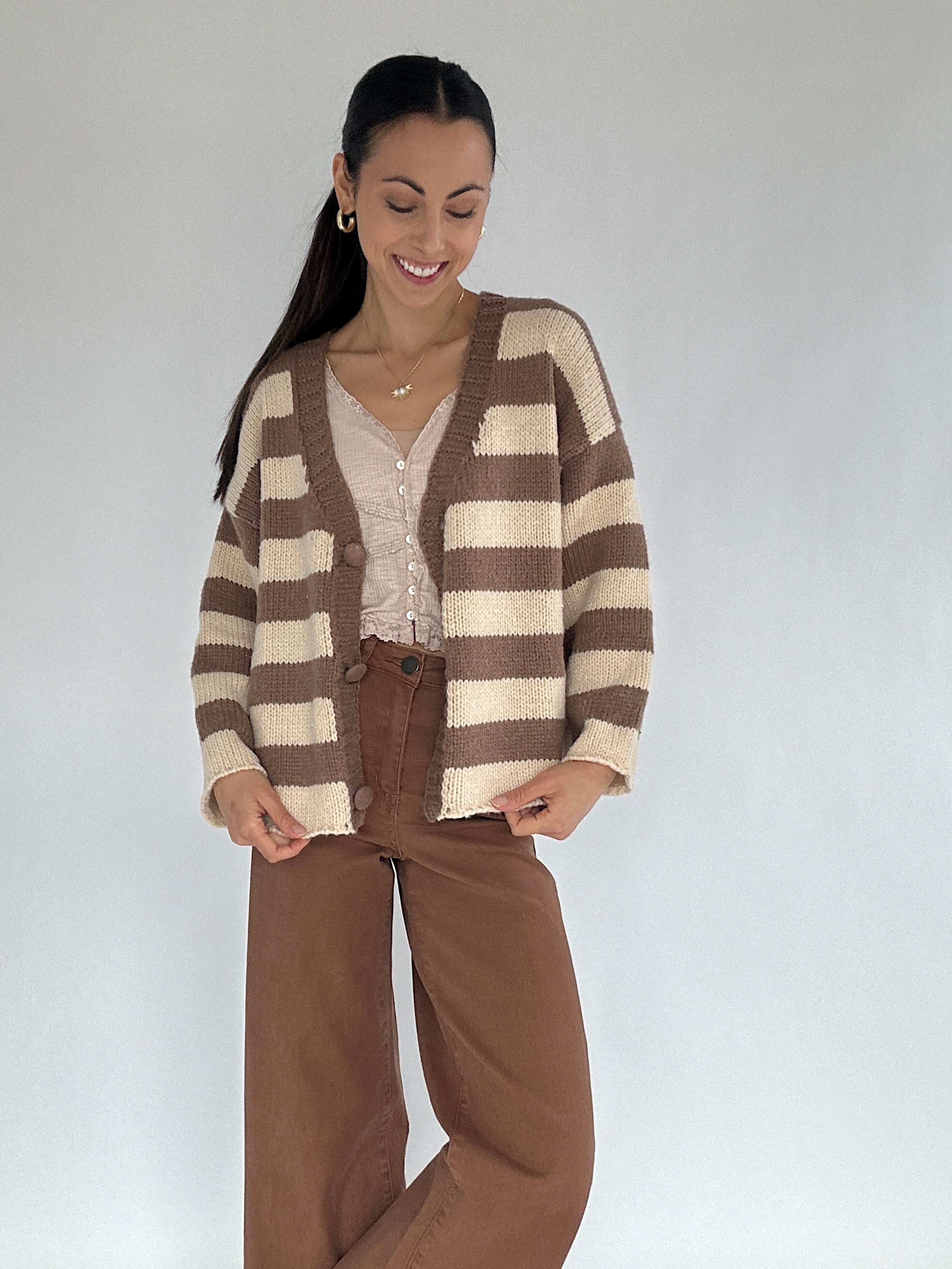 Woman wearing a brown and beige striped cardigan on a plain background