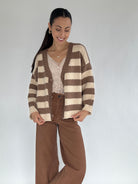 Woman wearing a brown and beige striped cardigan on a plain background