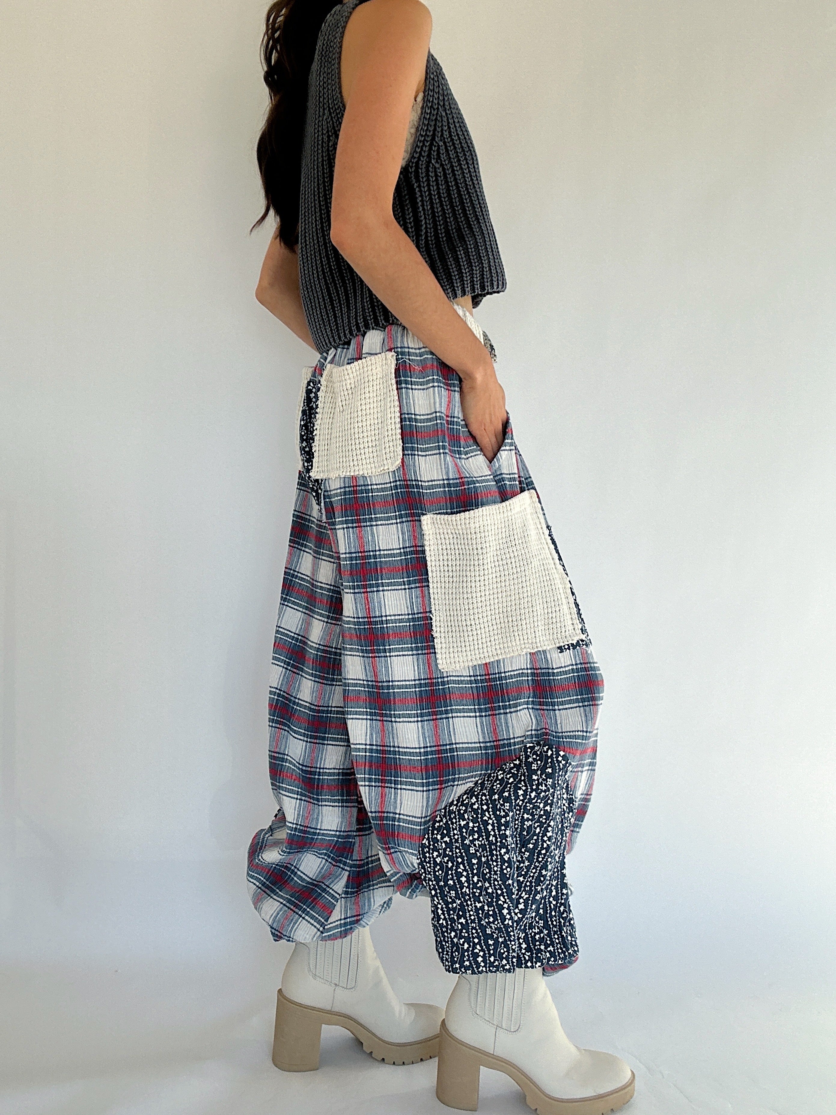 Person wearing plaid jogger style pants with textured patchwork and side pockets on a plain background showing side view