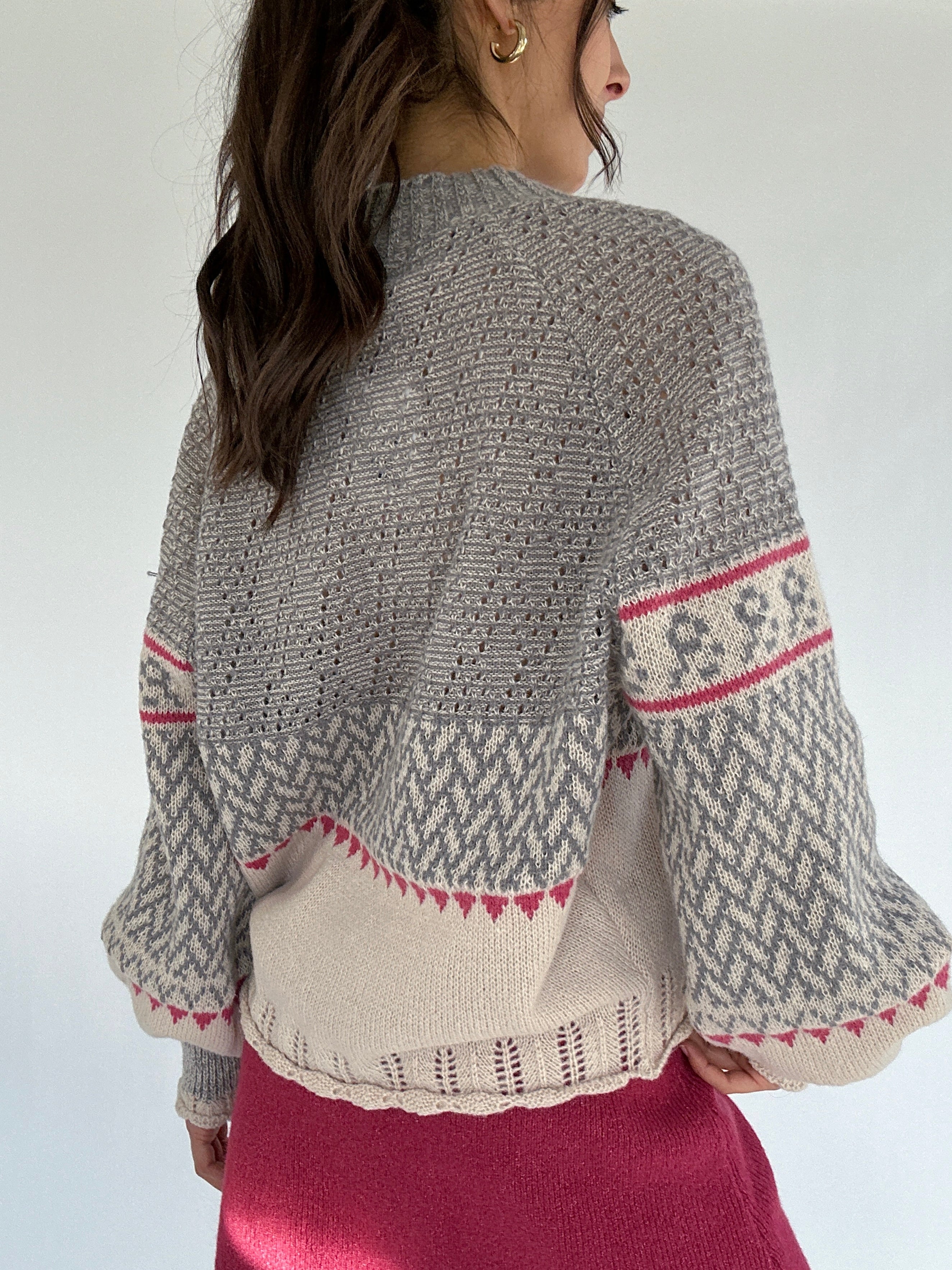 Person wearing a grey patterned sweater with a plain background