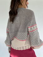 Person wearing a grey patterned sweater with a plain background