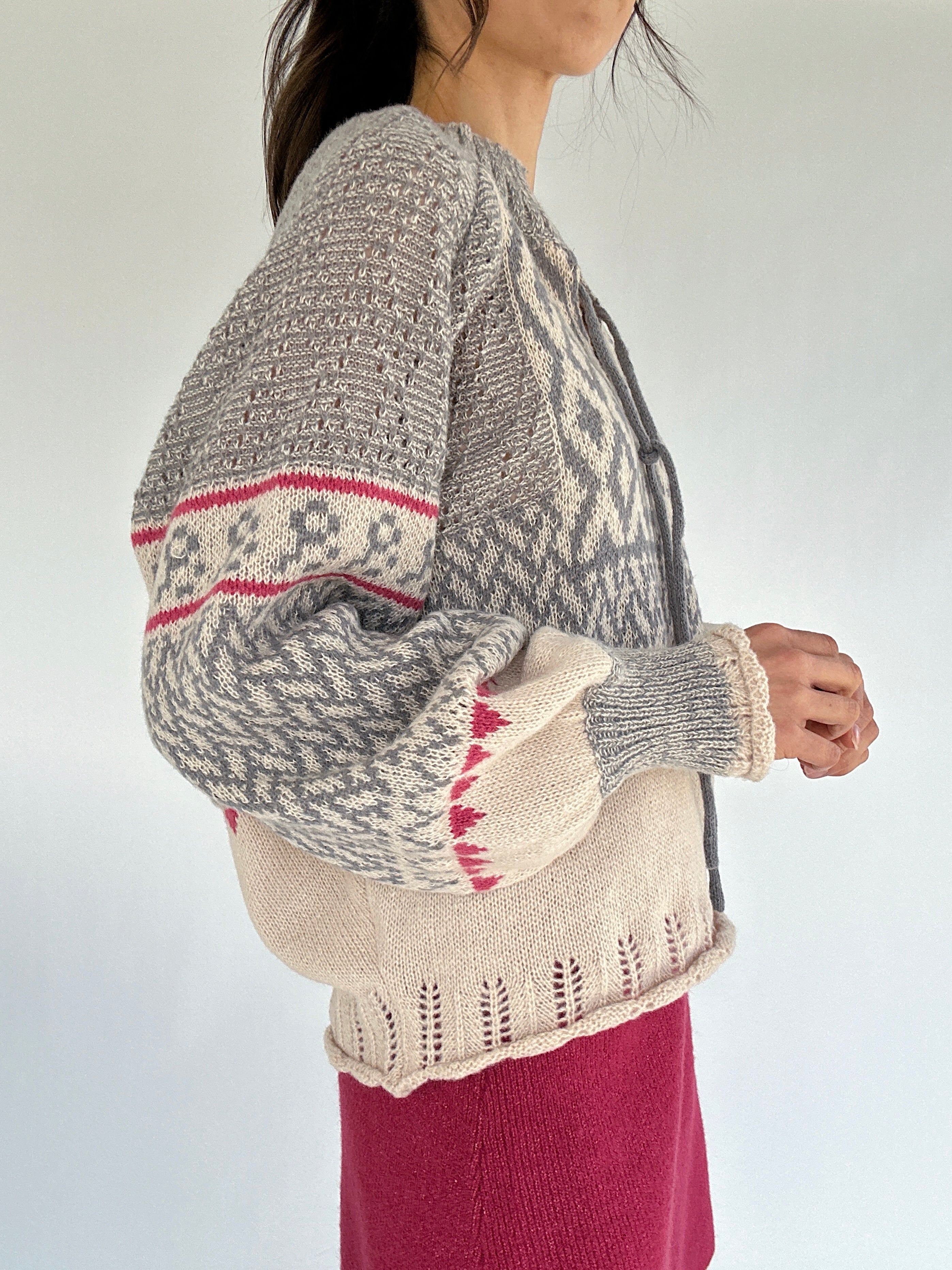 Person wearing a patterned sweater with a neutral background from side